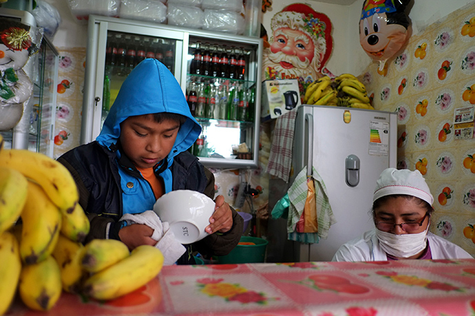 A boy dries a bowl at a food stall where he works, in La Paz (Reuters / David Mercado)