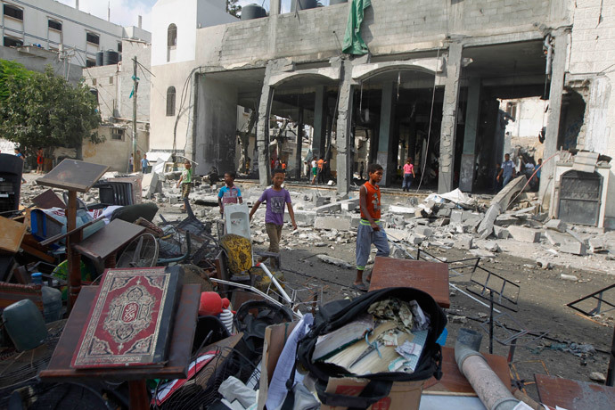 Palestinian boys walk past debris, including Korans and other items from a mosque destroyed in an overnight Israeli military strike, on July 22, 2014, in Rafah the southern Gaza Strip. (AFP Photo / Said Khatib)