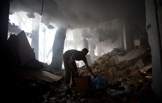 A Palestinian man removes goods from the rubble of a destroyed store located on the ground floor of a building hit by an Israeli air strike on July 22, 2014 in Gaza city. (AFP Photo / Mahmud Hams) 