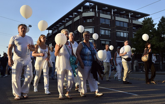People wearing white clothes hold balloons during a silent march in memory of the victims of the downed Malaysia Airlines flight MH17, on July 23, 2014 in Amsterdam. (AFP Photo / John Thys)