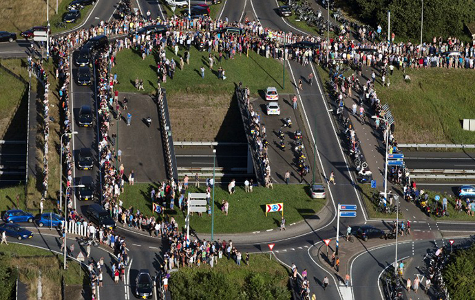 An aerial view taken on July 23, 2014 shows people standing on the side of the road as the convoy of hearses carrying the bodies of victims of the downed Malaysia Airlines flight MH17 is on its way to Hilversum where the bodies will be examined. (AFP Photo / Jerry Lampen)