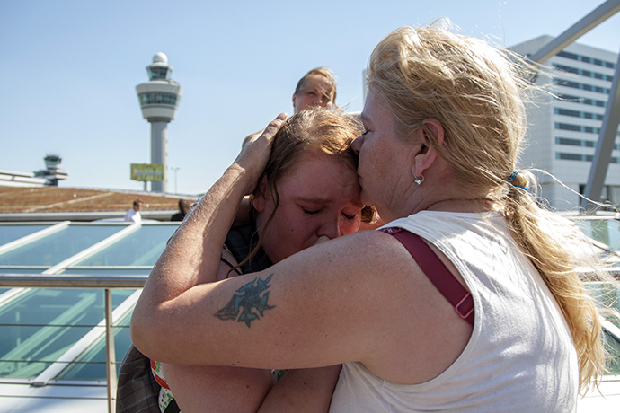 People embrace while paying their respects at Schiphol Airport during a national day of mourning for the victims of the downed Malaysia Airlines flight MH17, in Schiphol July 23, 2014. (Reuters / Cris Toala Olivares)