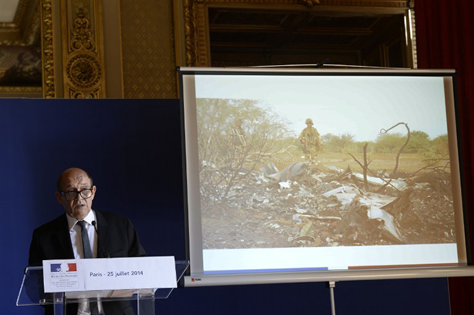 French Defence minister Jean-Yves Le Drian delivers a press conference at the Quai d'Orsay on June 25, 2014 with behind him an image released by ECPAD showing French soldiers standing by the wreckage of the Air Algerie flight AH5017 which crashed in Mali's Gossi region, west of Gao, the day before. (AFP Photo / Stephane de Sakutin)