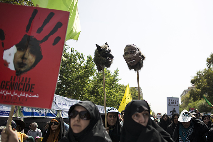 Iranian women hold up a mask of US President Barak Obama and a wolf during a demonstration in Tehran on July 25, 2014 to mark Quds (Jerusalem) Day. (AFP Photo / Behrouz Mehri)