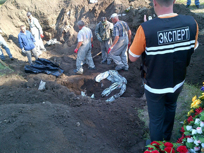 Experts dig a hole to exhume four unidentified bodies at a mass grave in the eastern Ukrainian city of Slavyansk on July 24, 2014. (AFP Photo / Marion Thibaut)