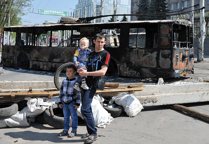 A man with his children stands near a trolleybus which was burned overnight during fightings between anti-government militias and Ukranian troops in the eastern Ukranian city of Kramatorsk. (AFP Photo / Genya Savilov)