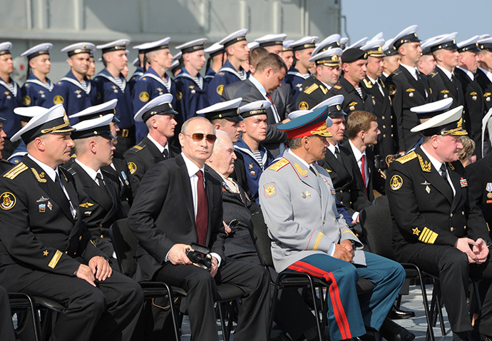 Russian President Vladimir Putin, 1st row 3rd left, is seen on board the Admiral Kuznetsov aircraft carrier watching a parade and a staged performance by combat ships of Russia's Northern Fleet, July 27, 2014. (RIA Novosti / Michael Klimentyev)