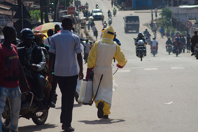 A health worker with disinfectant spray walks down a street outside the government hospital in Kenema, July 10, 2014 (Reuters / Tommy Trenchard)