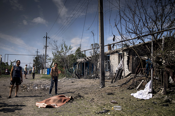 Local residents are seen near the body of a local resident killed in the Ukrainian armed forces' air attack on the village of Luganskaya (RIA Novosti / Valery Melnikov)