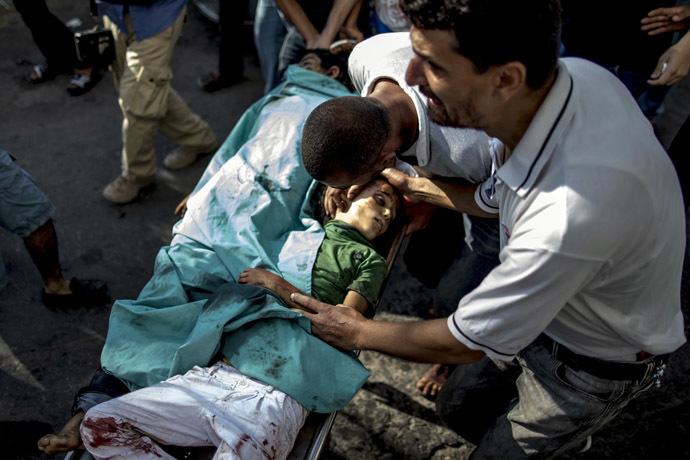 A Palestinian man mourns over the bodies of two children, killed in an explosion in a public playground on the beachfront of Shati refugee camp, as they are wheeled into al-Shifa hospital in Gaza City on July 28, 2014. (AFP Photo/Marco Longari)