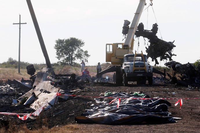 A crane moves wreckage at the crash site of Malaysia Airlines Flight MH17 in front of body bags near the village of Hrabove, Donetsk region, July 20, 2014.(Reuters / Maxim Zmeyev )