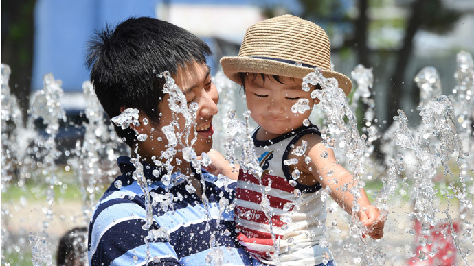 A father and his son enjoy bathing in the fountain at a park in Tokyo.(AFP Photo / Toru Yamanaka )