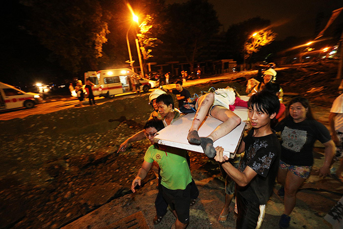 Residents carry a wounded person following a blast in the city of Kaohsiung in southern Taiwan early on August 1, 2014 (AFP Photo / Stringer)
