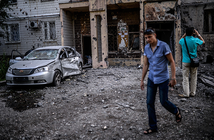 People look at a damaged area after shelling in Donetsk on July 29, 2014. (AFP Photo / Bulent Kilic)