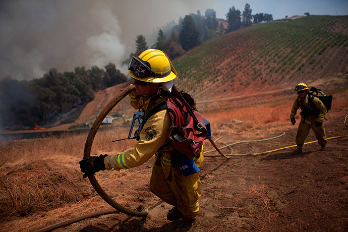 Marin County firefighters haul a hose on a fire line while battling the fast-moving wildfire called "Sand Fire," near Plymouth, California July 26, 2014. (Reuters / Max Whittaker)