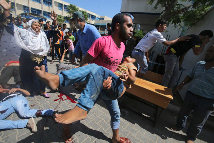 A Palestinian carries a wounded boy following what witnesses said was an Israeli air strike at a United Nations-run school, where displaced Palestinians take refuge, in Rafah in the southern Gaza Strip August 3, 2014.(Reuters / Ibraheem Abu Mustafa)