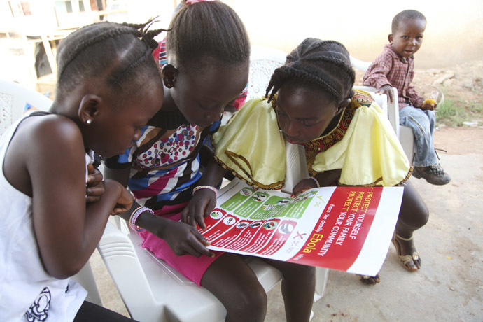 Girls look at a poster, distributed by UNICEF, bearing information on and illustrations of best practices that help prevent the spread of Ebola virus disease (EVD), in the city of Voinjama, in Lofa County, Liberia in this April 2014 UNICEF handout photo. (Reuters/UNICEF)