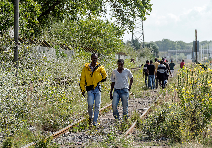 Migrants walk on a railway in Calais, northern France, on August 5, 2014 (AFP Photo / Pilippe Huguen)