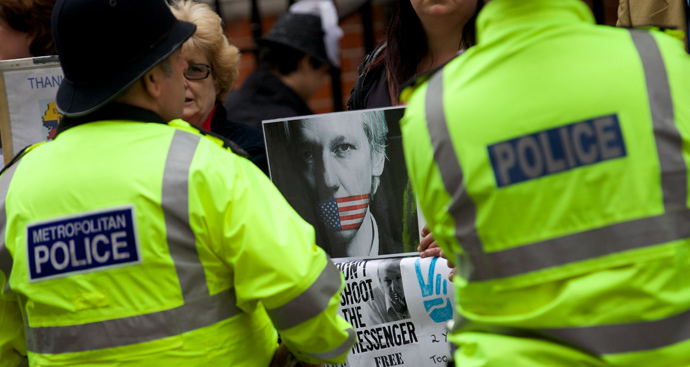 Police stand guard in front of supporters of WikiLeaks founder Julian Assange who are standing with banners outside the Ecuadorian Embassy in London on June 19, 2014 (AFP Photo / Andrew Cowie) 