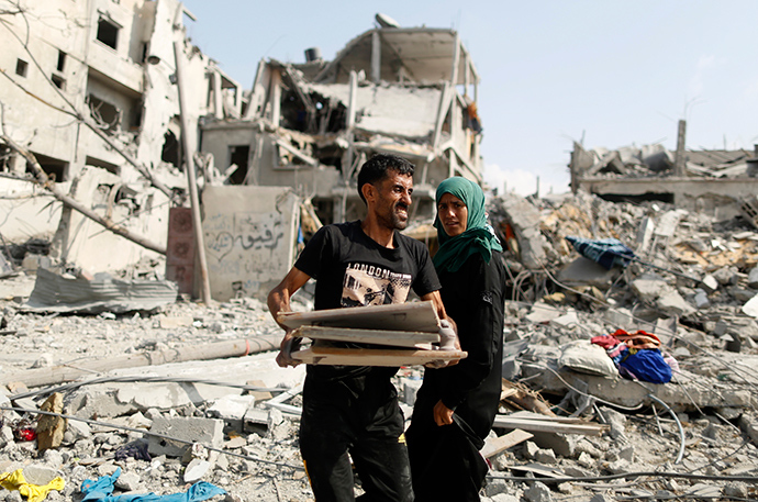 A Palestinian man carries his belongings after returning to his destroyed house in Beit Hanoun town, which witnesses said was heavily hit by Israeli shelling and air strikes during the Israeli offensive, in the northern Gaza Strip August 5, 2014 (Reuters / Suhaib Salem)