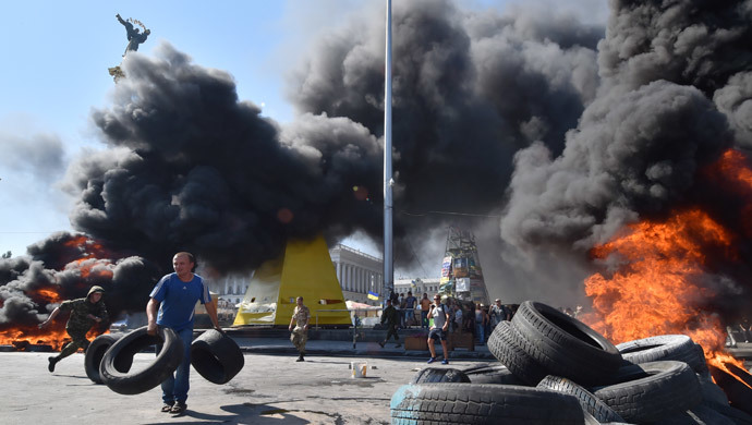 A man holds tires as Maidan self-defence activists clash with fighters of Kiev-1 volunteer battalion on Independence Square in Kiev on August 7, 2014. (AFP Photo / Sergei Supinsky)