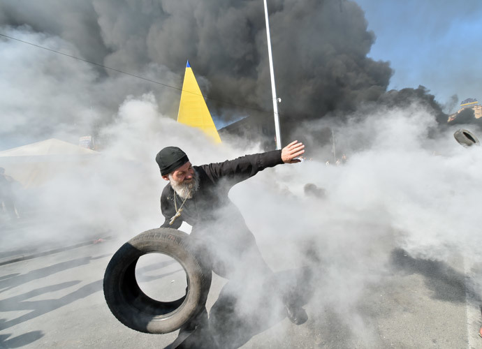 An Orthodox priest throws a tyre as Maidan self-defence activists clash with fighters of Kiev-1 volunteer battalion on Independence Square in Kiev on August 7, 2014.(AFP Photo / Sergei Supinsky )