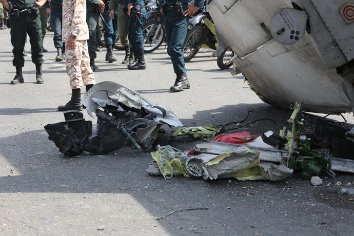 Iranian Revolutionary Guards and security forces stand next to the remains of a plane as they secure the scene of a crash near Tehran's Mehrabad airport on August 10, 2014. (AFP Photo / Atta Kenare)