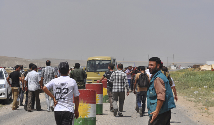 Displaced families from the minority Yazidi sect, fleeing the violence, walk on the outskirts of Sinjar, west of Mosul (Reuters / Stringer)