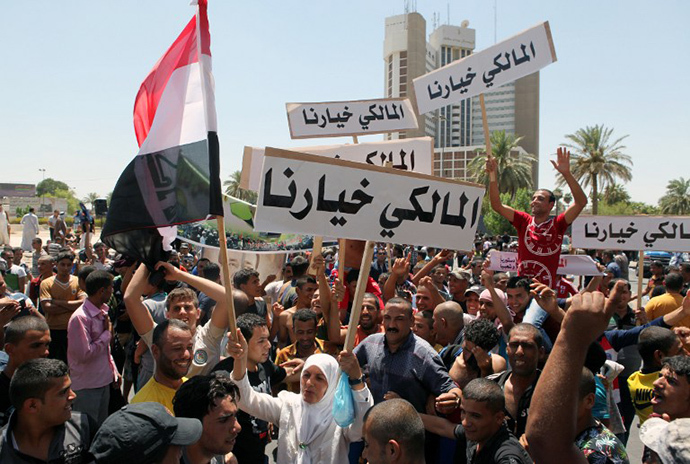 Iraqis hold placards reading in Arabic "Maliki is our choice" during a demonstration to support Iraq's prime minister on August 11, 2014 in Baghdad's central Saadoun Street after Nuri al-Maliki said he was filing a complaint against the president for violating the constitution. (AFP Photo / Amer Al-Saedi)