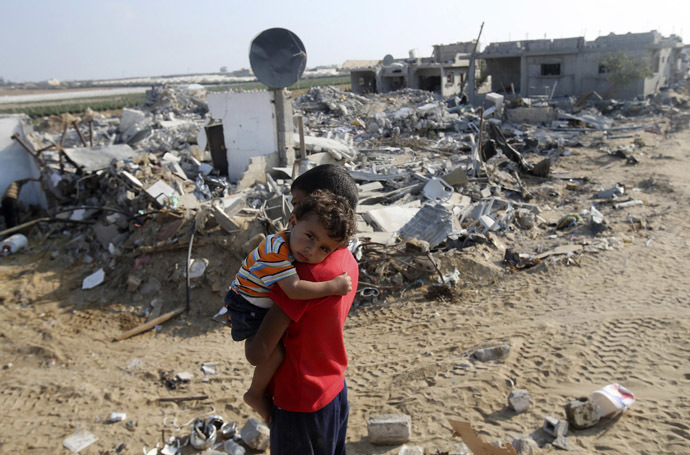 A Palestinian boy carries his brother next to the remains of their house, which witnesses said was destroyed in the Israeli offensive, during a 72-hour truce in Khan Younis the southern Gaza Strip August 13, 2014. (Reuters/braheem Abu Mustafa)