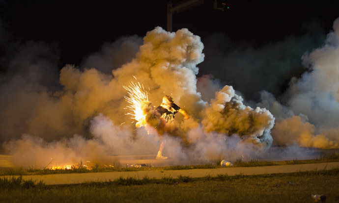 A protester throws back a smoke bomb while clashing with police in Ferguson, Missouri August 13, 2014. (Reuters)