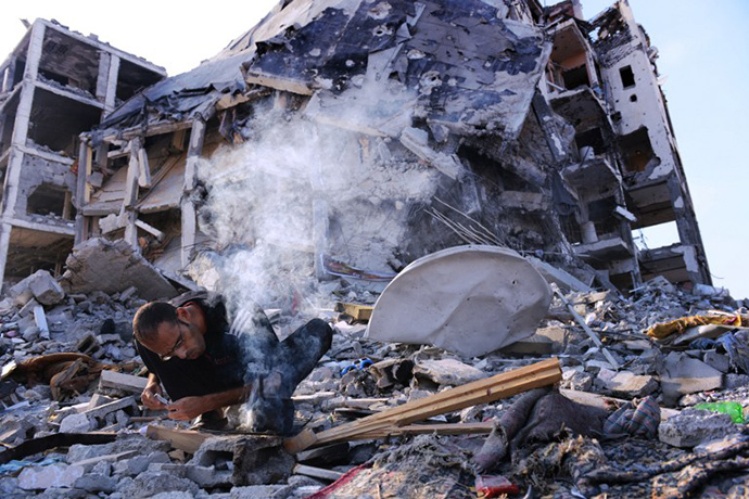 Mohammed Abu Ghama starts a small fire to heat water for tea under a destroyed tower of an apartment complex which he calls home and that was heavily damaged in fighting between Israel and Hamas during over 4 weeks of fighting in northern Gaza strip a few miles away from the border with Israel on August 13, 2014. (AFP Photo / Roberto Schmidt)