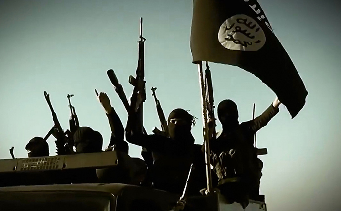 An image grab taken from a propaganda video allegedly shows ISIL fighters raising their weapons as they stand on a vehicle mounted with the trademark Jihadists flag at an undisclosed location in the Anbar province. (AFP Photo)