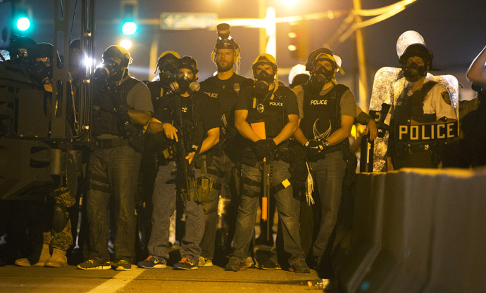 Police officers keep watch while demonstrators (not pictured) protest the death of black teenager Michael Brown in Ferguson, Missouri August 12, 2014. (Reuters / Mario Anzuoni) 