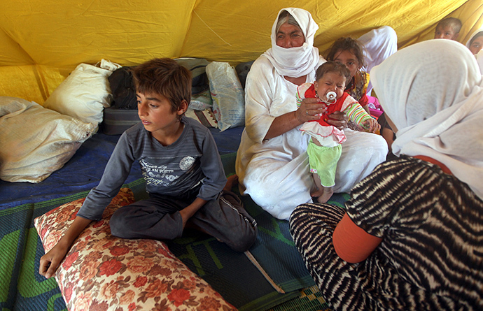 An Iraqi Yazidi refugee family sits inside a tent at Newroz camp in Hasaka province, north eastern Syria on August 14, 2014, after fleeing Islamic State militants in Iraq. (AFP Photo / Ahmad Al-Rubaye)