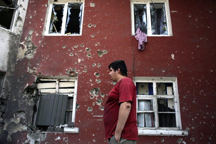 A young resident walks past damaged buildings on August 14, 2014 in the small eastern Ukrainian city of Vuglegirsk, freed by the Ukraine's forces three days ago, in the Donetsk region. (AFP Photo / Anatolii Stepanov)