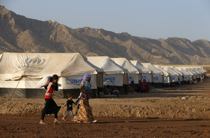 Displaced people from the minority Yazidi sect, who fled the violence in the Iraqi town of Sinjar, walk in Bajed Kadal refugee camp south west of Dohuk province August 15, 2014 (Reuters / Youssef Boudlal)