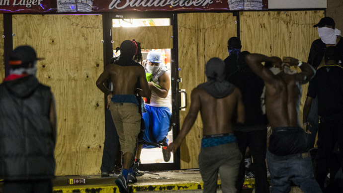 A masked man carries items out of a liquor store that had been broken into during on-going demonstrations to protest against the shooting of Michael Brown, in Ferguson, Missouri, August 16, 2014. (Reuters/Lucas Jackson)