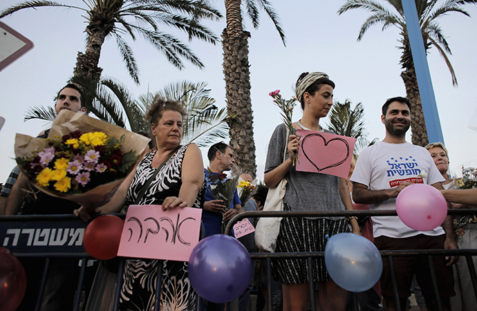 Protesters hold signs in support of the wedding of groom Mahmoud Mansour, 26, and bride Maral Malka, 23, outside a wedding hall in Rishon Lezion, near Tel Aviv August 17, 2014. (Reuters / Ammar Awad)