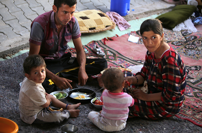 A displaced Iraqi family from the Yazidi community eat under a bridge where they found refuge after Islamic State (IS) militants attacked the town of Sinjar on August 17, 2014 on the outskirts of the Kurdish city of Dohuk, in Iraq's autonomous Kurdistan region. (AFP Photo / Ahmad Al-Rubaye)