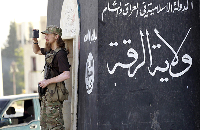 A militant Islamist fighter uses a mobile to film his fellow fighters taking part in a military parade (Reuters)