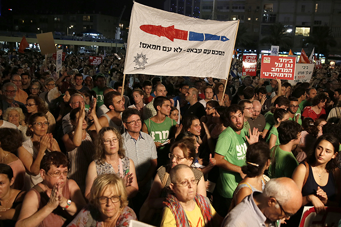 Demonstrators hold a placard reading in Hebrew: "Agreement with Abbas not with Hamas" as thousands of Israelis protest during a left-wing peace rally in the coastal city of Tel Aviv calling for the Israeli government to negotiate with the Palestinian Authority on August 16, 2014. (AFP Photo / Gali Tibbon)