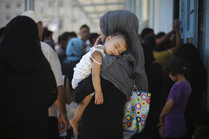A Palestinian woman holds her daughter as she waits to receive food supplies from a United Nations food distribution center in Khan Younis in the southern Gaza Strip August 19, 2014. (Reuters / Ibraheem Abu Mustafa)