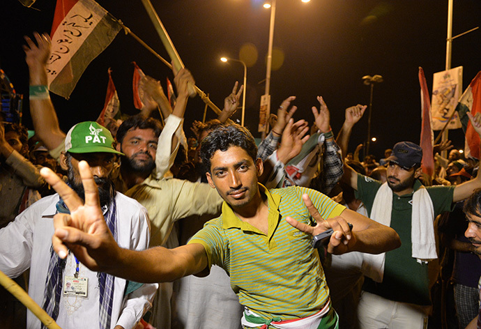 Pakistani supporters of Canada-based preacher Tahir-ul-Qadri dance as they gather in front of the parliament building during the "Revolution March" protest in Islamabad on August 20, 2014. (AFP Photo / Aamir Qureshi)