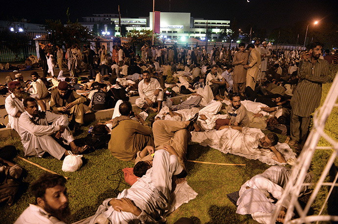 Pakistani supporters of Canada-based preacher Tahir-ul-Qadri (not pictured) rest in front of the parliament building during the "Revolution March" protest in Islamabad on August 20, 2014. (AFP Photo / Aamir Qureshi)