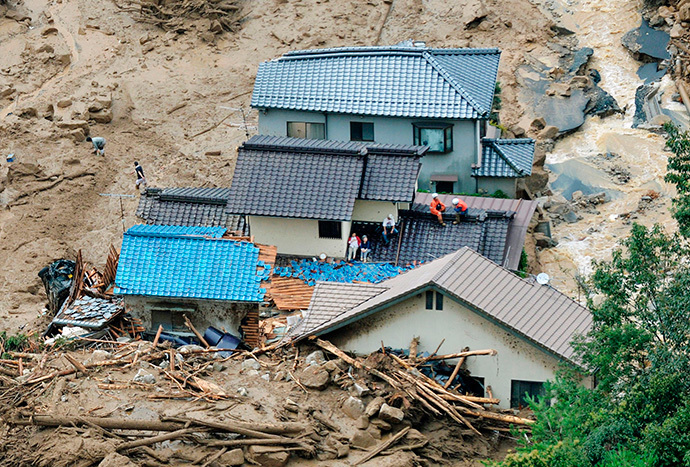 Local residents wait for rescue operation atop of collapsed houses as rescue workers stand by next to them, after a massive landslide swept through a residential area at Asaminami ward in Hiroshima, western Japan, in this photo taken by Kyodo August 20, 2014. (Reuters / Kyodo)
