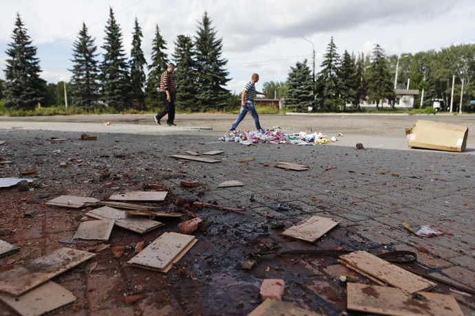 Local residents walk near bloodstains on a damaged street after recent shelling in the settlement of Makeyevka, on the outskirts of Donetsk, August 19, 2014. (Reuters/Maxim Shemetov)