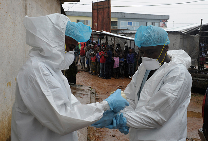 Health workers wear protective clothing before carrying an abandoned dead body presenting with Ebola symptoms at Duwala market in Monrovia August 17, 2014 (Reuters / 2Tango)