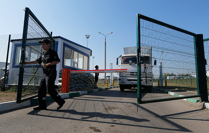 A Russian border guard opens a gate in front of a truck from a convoy that delivered humanitarian aid for Ukraine on its return to Russia at border crossing point "Donetsk" in Russia's Rostov Region August 23, 2014 (Reuters / Alexander Demianchuk)