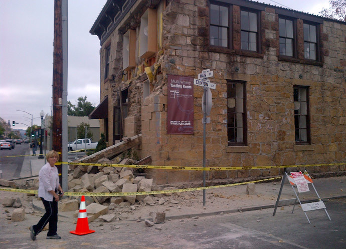 An unidentified woman walks past damage to a downtown building in Napa, California August 24, 2014.(Reuters / Jim Christie)
